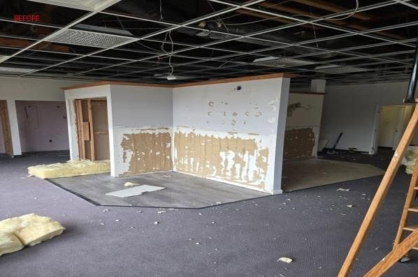 Commercial space mid-demolition with exposed ceiling and drywall removed